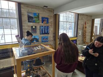 Students writing responses while viewing First Nations art